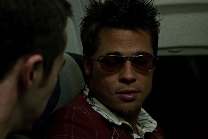 Man wearing sunglasses and a red plaid jacket in a dark setting illustrating women’s icks men gave them.