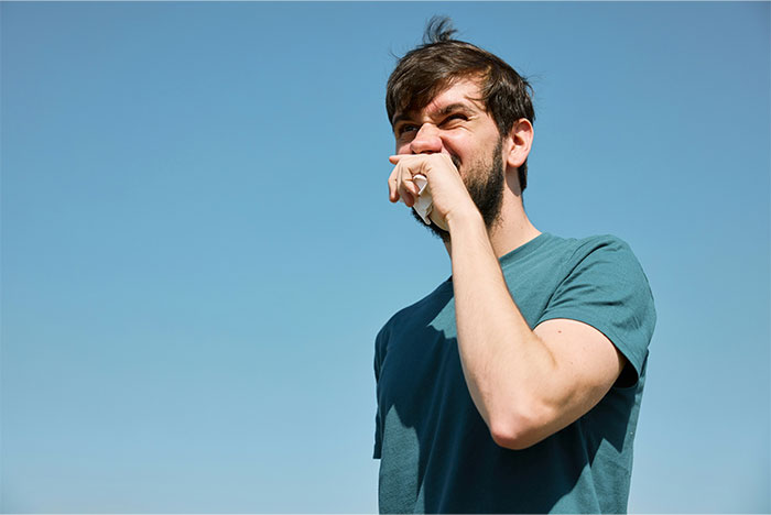 Man in a teal shirt holding his hand near his mouth outdoors, illustrating men giving icks to women.