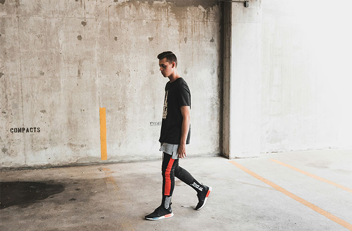 Young man walking in an urban parking garage showing signs of relationship icks women notice in men.