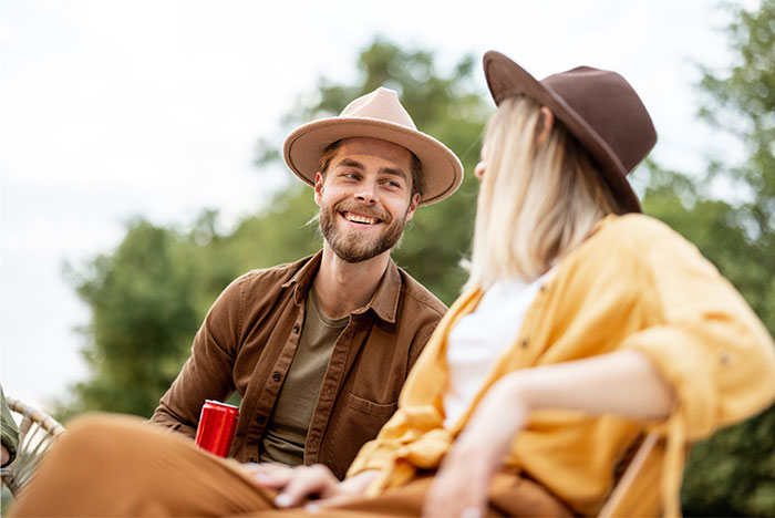 A man and woman wearing hats smiling and talking outdoors, illustrating women sharing icks men gave them.
