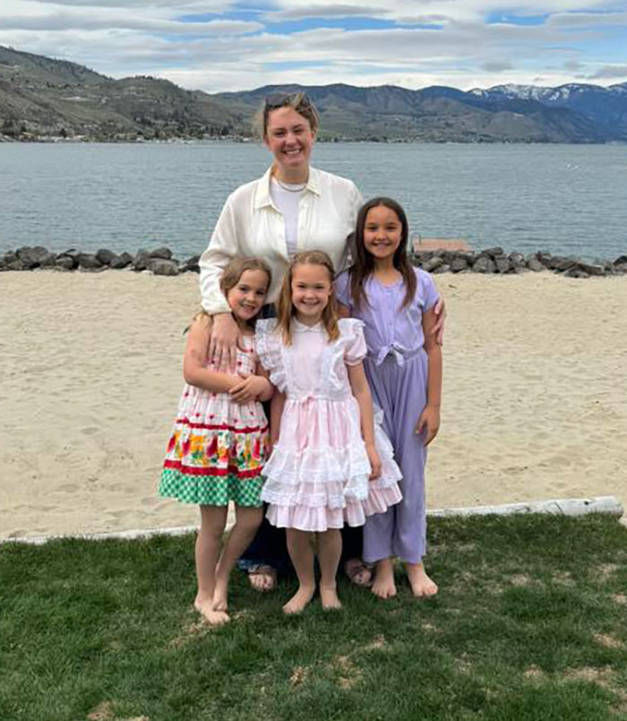 Three young sisters standing with an adult woman near a lakeside beach before their bodies were found missing.