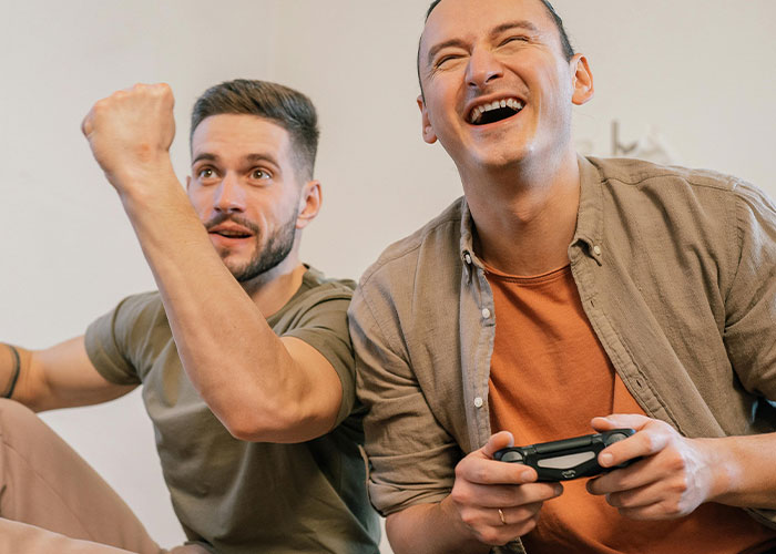 Two men enjoying a video game together, sharing a wholesome interaction with strangers in a joyful moment.