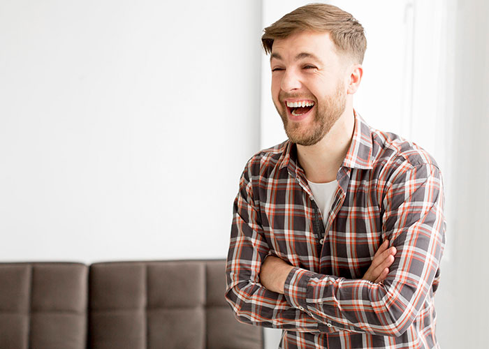 Young man laughing joyfully during a wholesome interaction with a stranger in a bright casual indoor setting