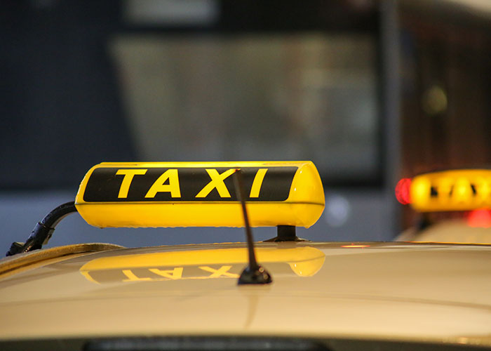 Yellow taxi sign on rooftop, reflecting light, illustrating wholesome interactions with strangers during rides.
