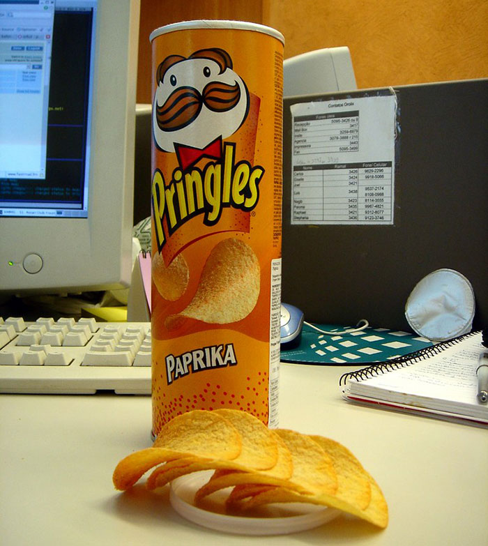 Pringles can with paprika chips spilled on a desk, illustrating product design flaws that cause daily user frustration.