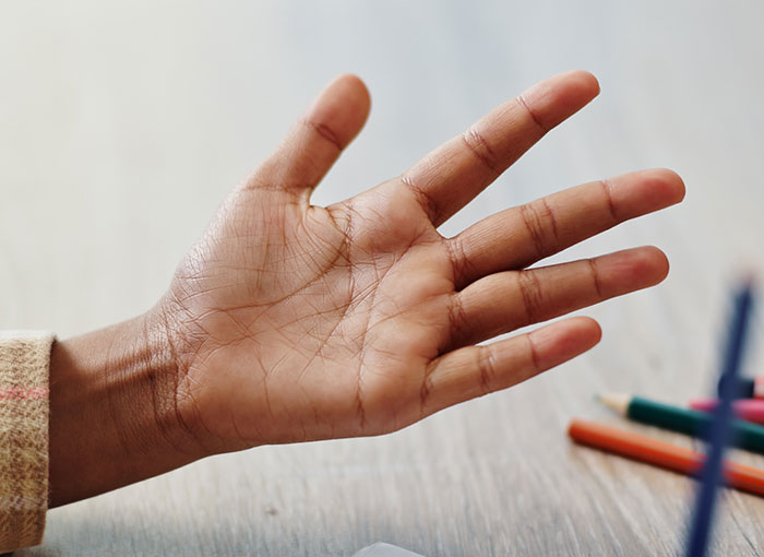 Close-up of a hand near colored pencils illustrating frustration with products with design flaws causing rage.