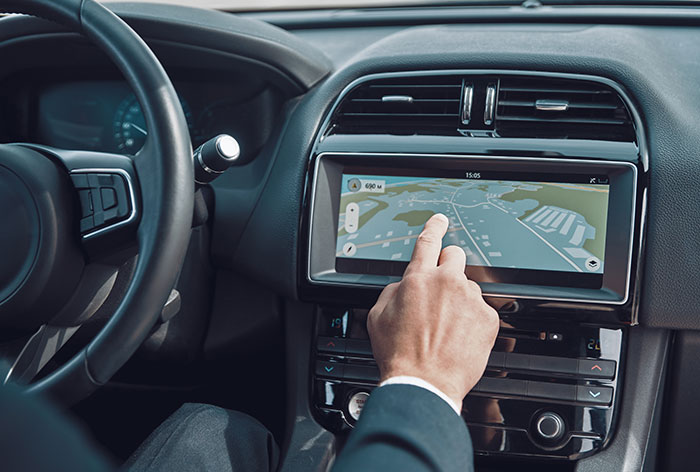 Person interacting with a car navigation system highlighting design flaws in automotive products causing user frustration.