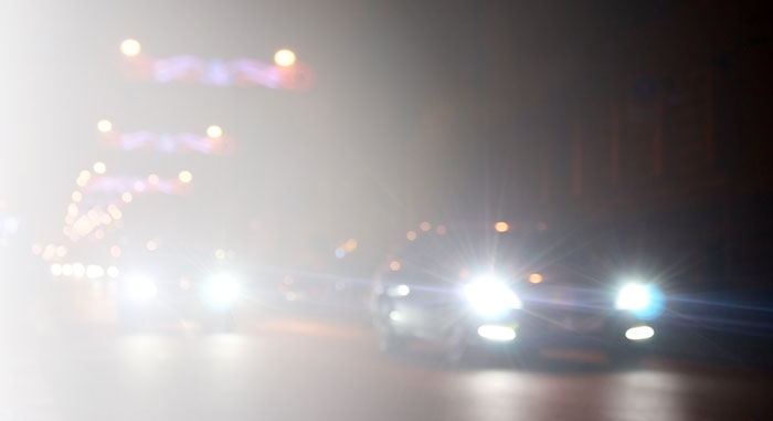 Blurry night scene of multiple cars with bright headlights causing glare illustrating design flaws in product visibility.
