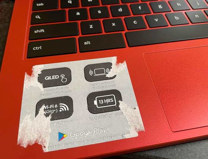 Partially peeled sticker on a red laptop showing design flaws that frustrate users of tech products.