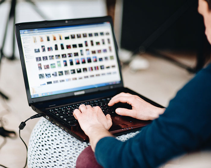 Person using a laptop to browse images, illustrating frustration with products that have design flaws causing rage.