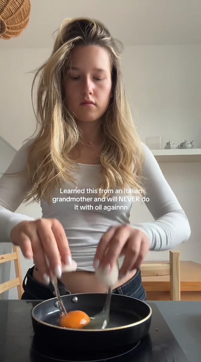 Woman frying eggs using a bizarre technique learned from her Italian grandmother in a modern kitchen setting. Woman frying eggs using a bizarre technique learned from her Italian grandmother in a modern kitchen setting.
