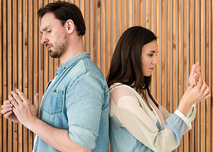 Couple standing back to back, looking upset, illustrating tension around being a tradwife in a modern relationship.