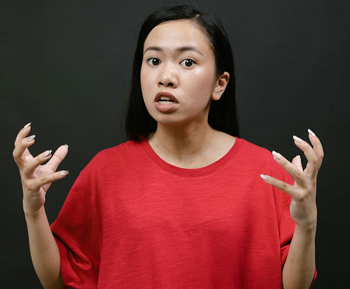 Young woman in red shirt expressing frustration while discussing kosher wedding meals cost and family expectations
