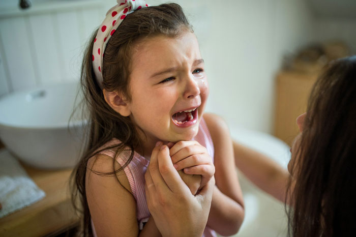 Young girl crying while woman holds her hands, depicting emotional distress related to woman refusing to watch sister again.