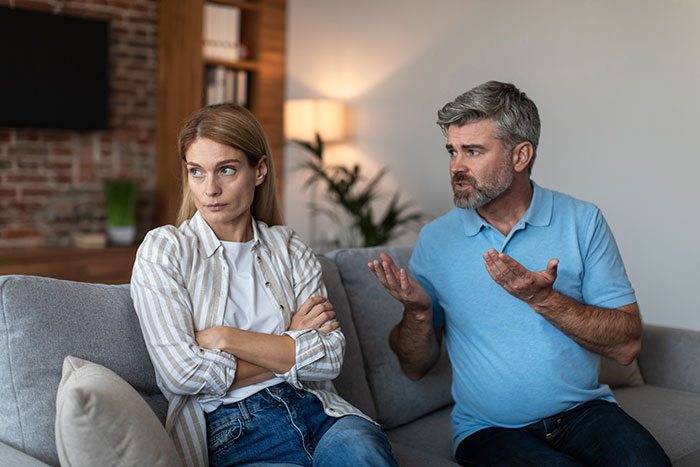 Couple having a tense conversation at home about paying for stepson’s surgery, showing frustration and disagreement. Couple having a tense conversation at home about paying for stepson’s surgery, showing frustration and disagreement.