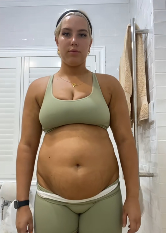Young woman in green workout clothes in bathroom, sharing her weight loss motivation and journey to lose 88lbs.