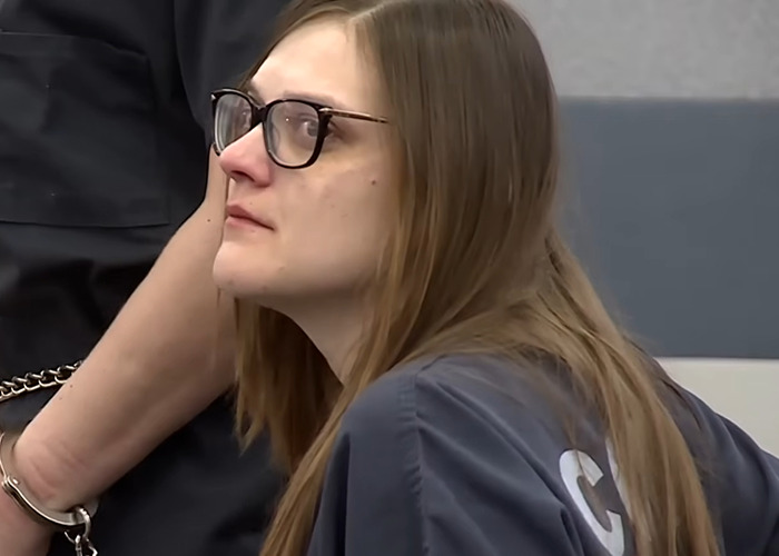 Woman wearing glasses and prison uniform in court, related to case of woman who slew boyfriend after finding tampon.