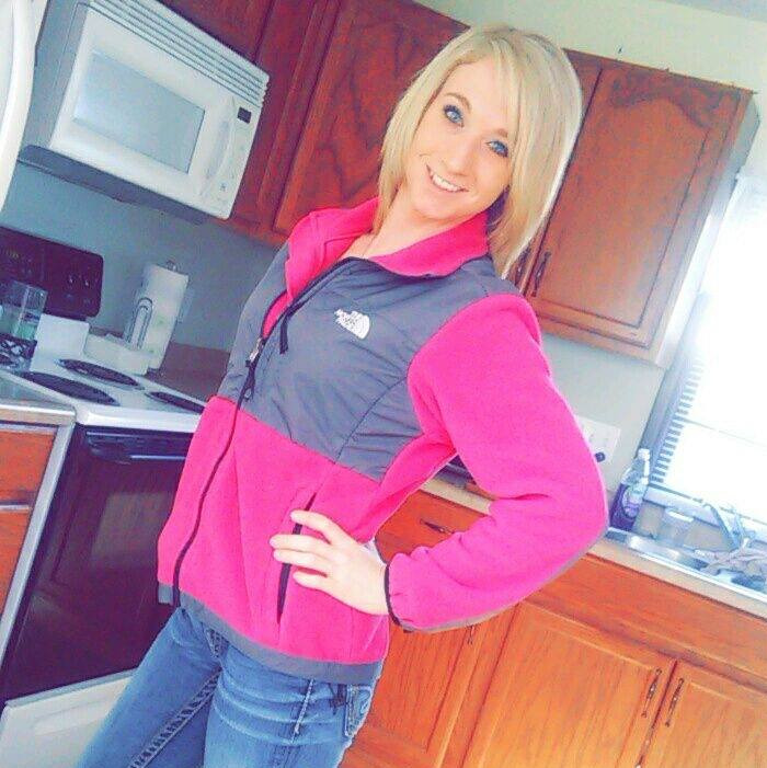 Young caring mother posing in kitchen wearing pink jacket, known for portion of jaw missing before naming alleged attacker.