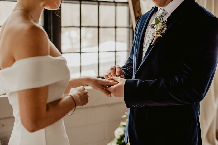 Couple exchanging rings during wedding ceremony, highlighting themes of disrespectful partner’s family experiences.