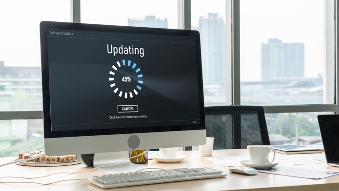 Work laptop updating screen on office desk, symbolizing employee sabotage after seeing colleagues' special treatment. Work laptop updating screen on office desk, symbolizing employee sabotage after seeing colleagues' special treatment.