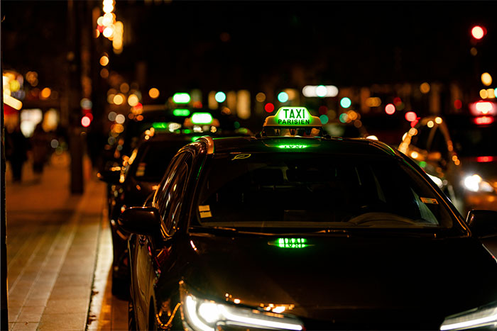 Row of parked taxis at night with illuminated signs, capturing the atmosphere where servers witness the worst dates at work.