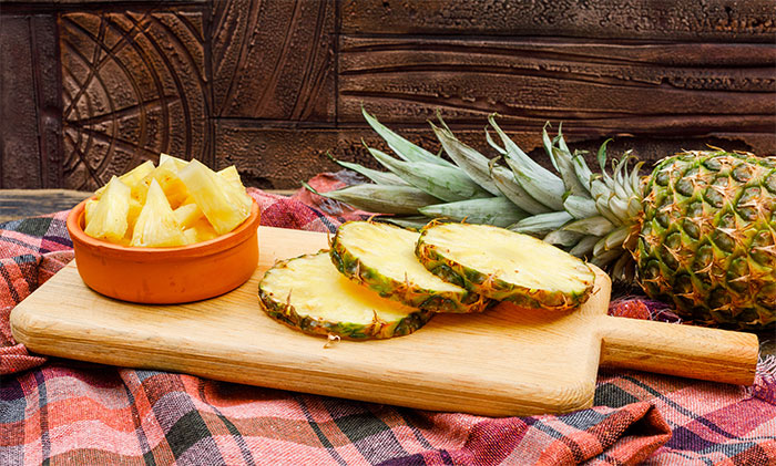 Fresh pineapple slices and chunks on a wooden board, illustrating servers sharing the worst dates witnessed at work experiences.