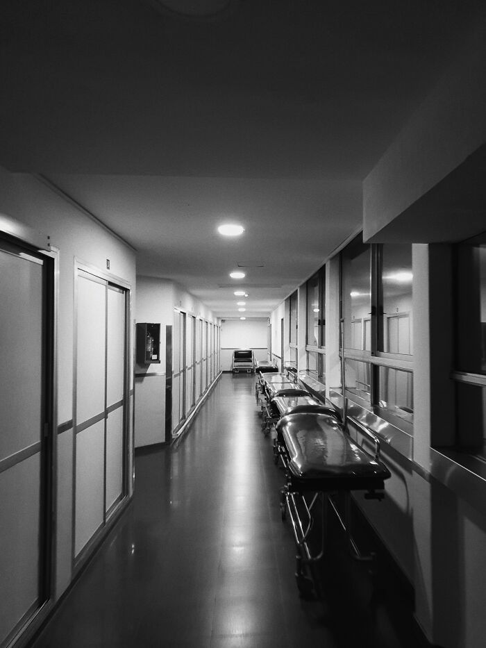 Empty hospital hallway at night with stretchers lined up, evoking a sense of awkward moments and creepy vibes.