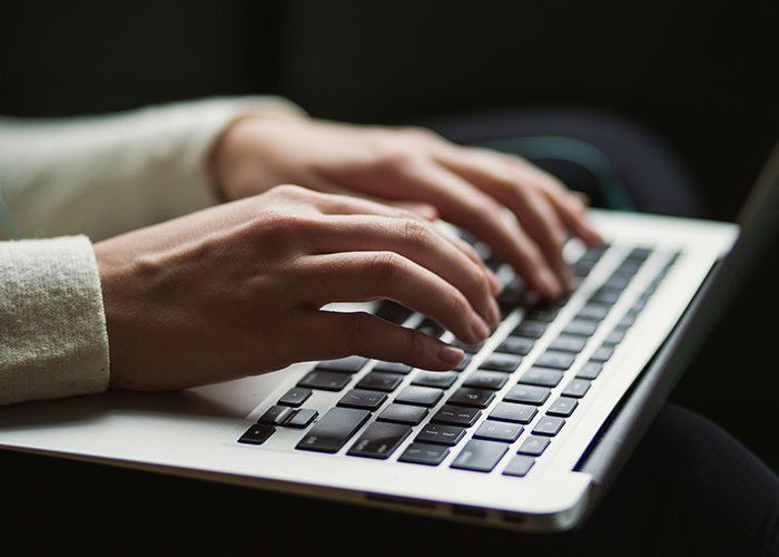 Person typing on a laptop keyboard illustrating office behavior in a workplace setting related to how to behave at work.