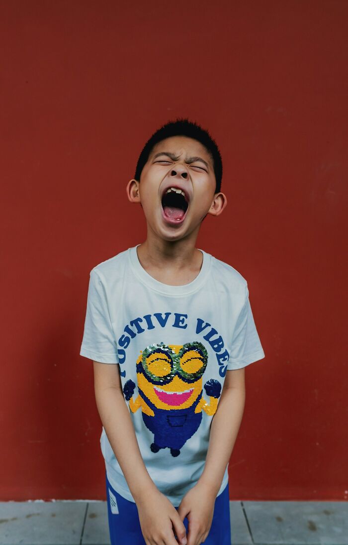 Young boy expressing emotion in a white shirt with positive vibes text, capturing authentic moments for SEO keyword purposes.