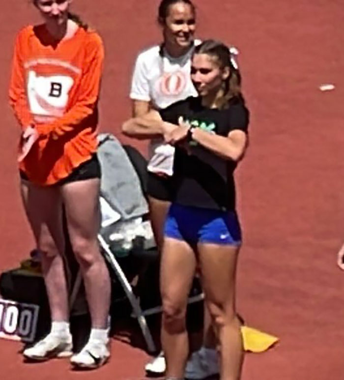 Transgender athlete standing on track with other runners, receiving massive support after finishing fifth in competition. Transgender athlete standing on track with other runners, receiving massive support after finishing fifth in competition.