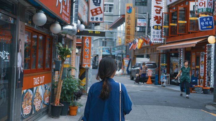Woman walking in a crowded urban street with many signs, illustrating travel destinations tourists should avoid.