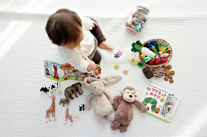 Baby playing with toys including stuffed animals and plastic figures, illustrating changes in industries impacted by millennials.