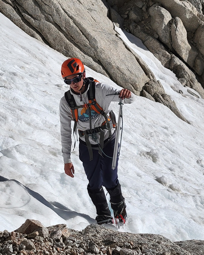 Teen climber wearing helmet and gear navigating a snowy mountain slope, highlighting terrifying words hallucinating son before cliff fall.