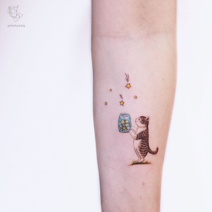 Small tattoo of a cat holding a jar with glowing stars, a creative and charming design popular in best tattoos collections.