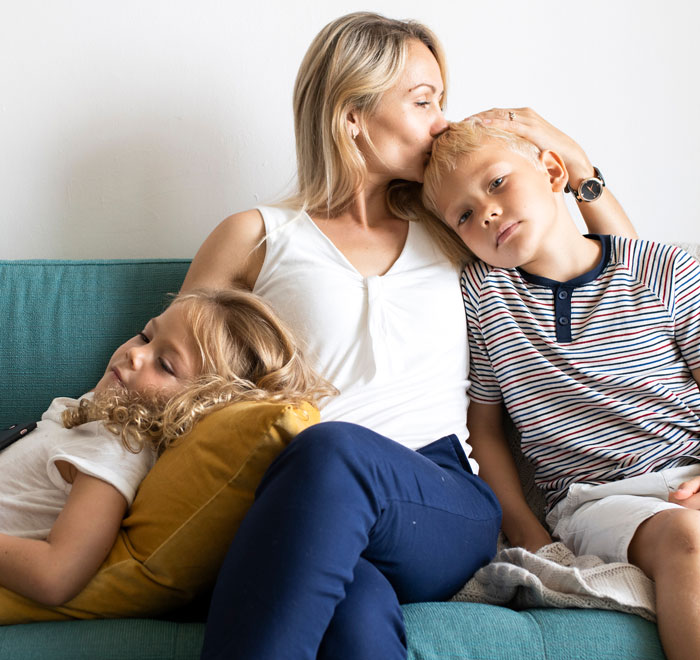 Mother showing affection to son and step-daughter while sitting on a couch, highlighting family dynamics and bonding. - 1