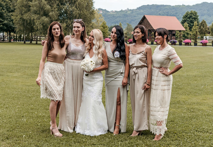 Bride and bridesmaids wearing neutral dresses outdoors, highlighting the contrast with the expectation of wearing color.