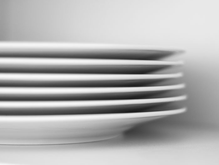 Stack of oldschool white ceramic plates representing outdated home trends millennials avoid.