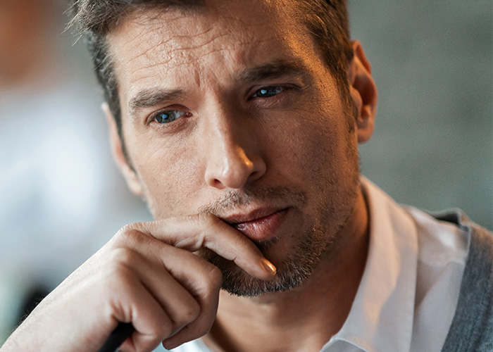 Man with blue eyes thinking deeply, representing employee complaints received by managers and HR teams.