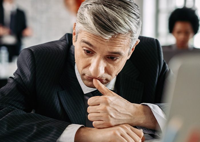 Businessman in a suit looking stressed while reviewing ridiculous complaints managers and HR received from employees.
