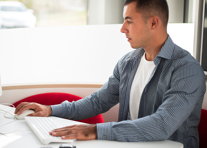Young employee at desk using computer, illustrating ridiculous complaints managers and HR received from employees.
