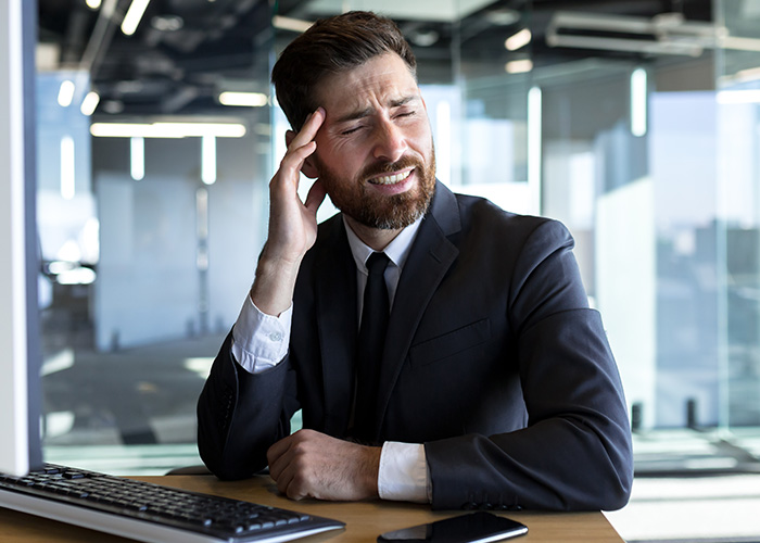 Man in business suit at office desk looking frustrated, illustrating ridiculous complains managers and HR received from employees