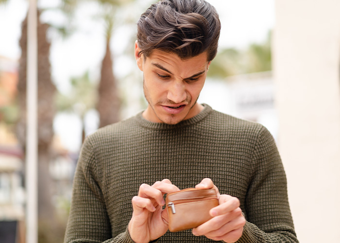 Young man with confused expression looking into a small brown pouch, illustrating ridiculous complaints from employees to managers and HR.