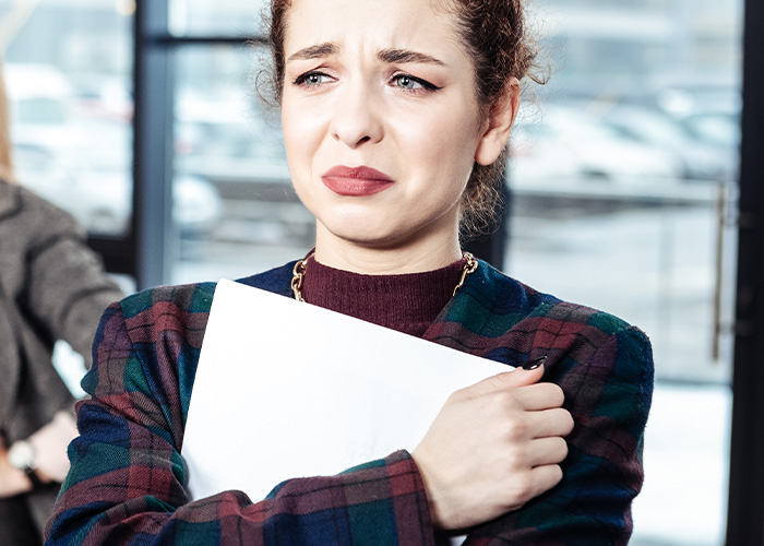 Woman looking upset while holding papers, illustrating ridiculous complaints managers and HR received from employees