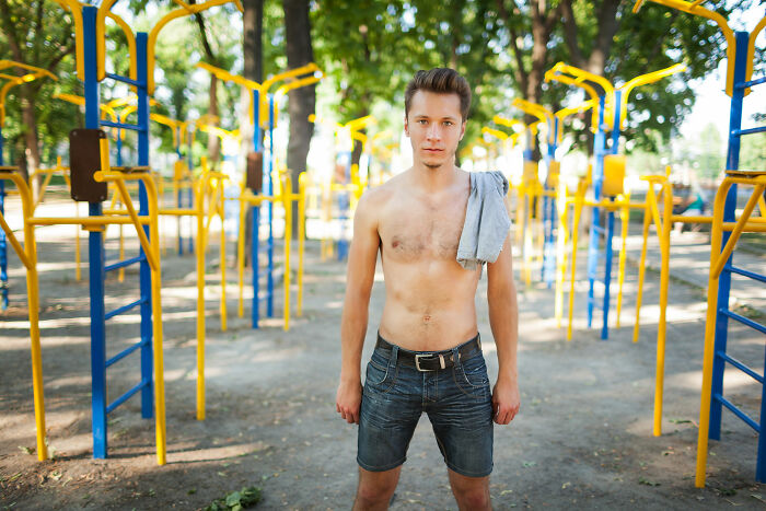 Shirtless young man standing in an outdoor gym area, illustrating things men find normal but seem bizarre to women.