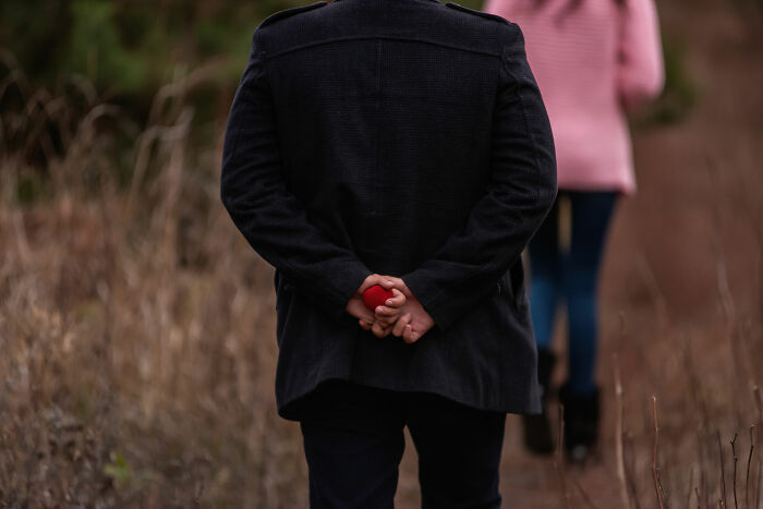 Person holding a small red heart behind their back while walking in a natural setting, evoking creepy real things witnessed.