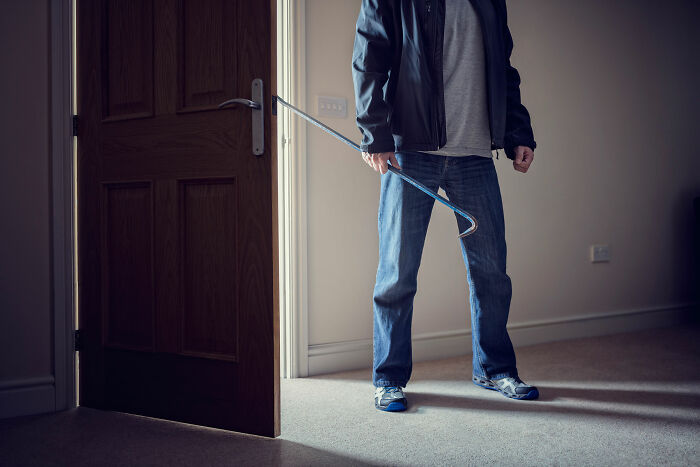 Person holding a crowbar standing in a dimly lit room, evoking a creepy real-life witnessed scenario.