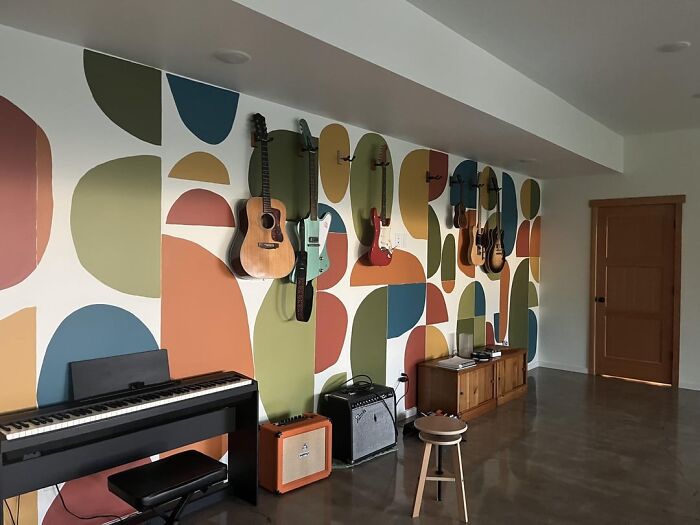 Living space revamped with colorful geometric wall art, guitars displayed, and musical instruments creating a creative music corner.