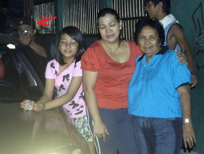 Group of people posing by a car at night with a mysterious figure holding a flashlight in the background, suggesting a terrifying backstory. - 19