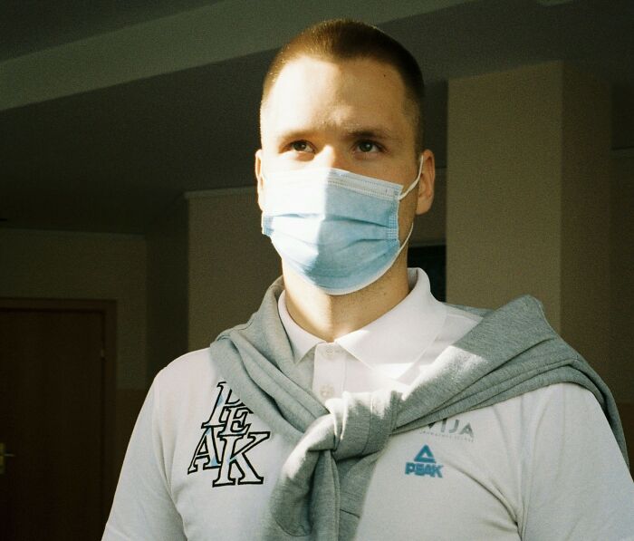 Man in a face mask wearing a white polo with a sweatshirt around shoulders, representing quiet down and stop screaming after birth.