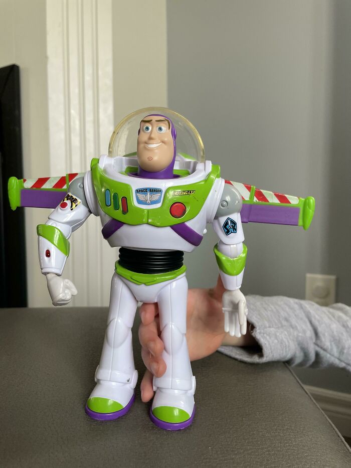 Buzz Lightyear toy figure in white and green space ranger suit held by a person on a gray surface for items found article.